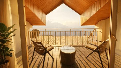 Room with balcony at Pride Premier Darjeeling featuring two chairs and a centre table facing towards the mountain view.