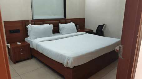 Regal Base Room at Bamboo Saa Sunrise Wedding & Wellness Resort, Jaipur featuring a king-size bed with wooden interiors and bedside tables.