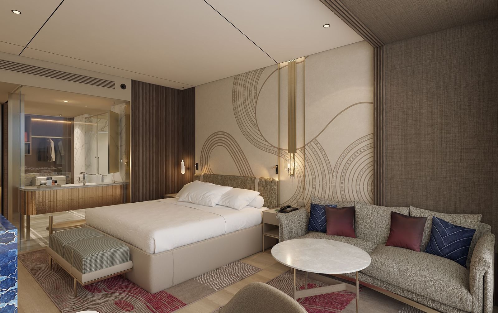A side view of a modern hotel room with a large bed, seating area featuring a sofa and round table, and a vanity mirror in the background at Merlis Hotel, Coimbatore