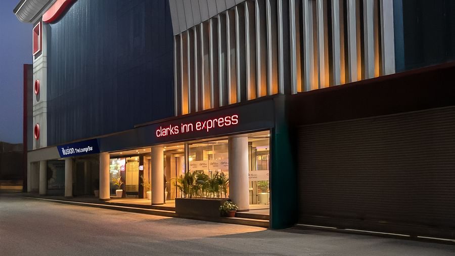 A modern building with a well-lit entrance, and a sleek exterior at dusk - Clarks Inn Express, Near Jammu Bari Brahmana Railway Station.