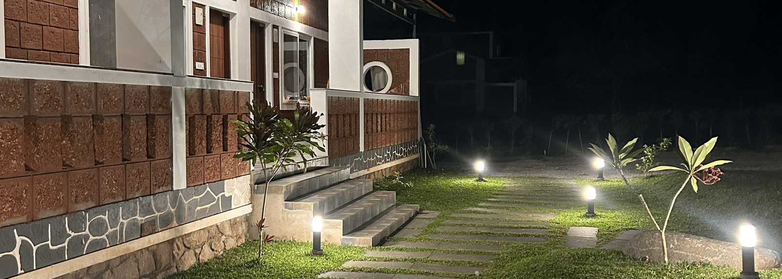 Hatti Eden Coorg | Facade with grass path with lights.