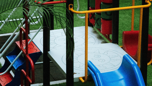 A colourful children's playground structure featuring a bright blue slide, climbing frames, and metal safety railings.
