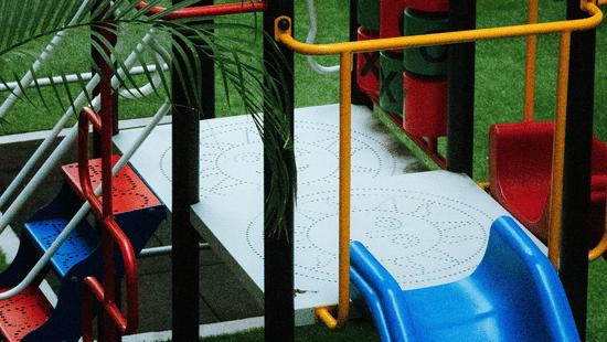 A colourful children's playground structure featuring a bright blue slide, climbing frames, and metal safety railings.