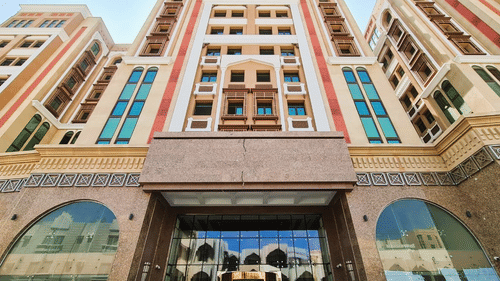 a view from below of La Maison Hotel, Doha with the entrance in view