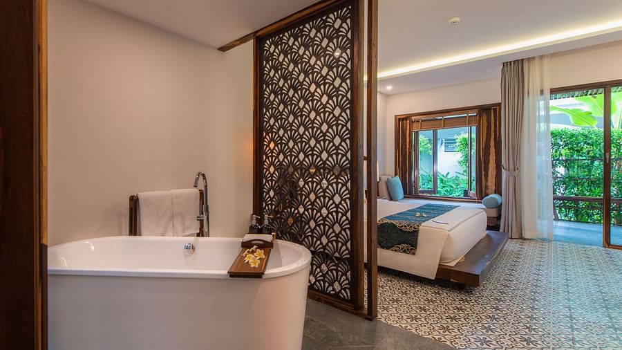 An image of a bath tub and a bed on the other room - Alibu Resort Nha Thrang