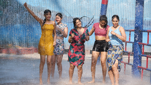 Group of women enjoying a splash zone under mist and water sprays at a water park.