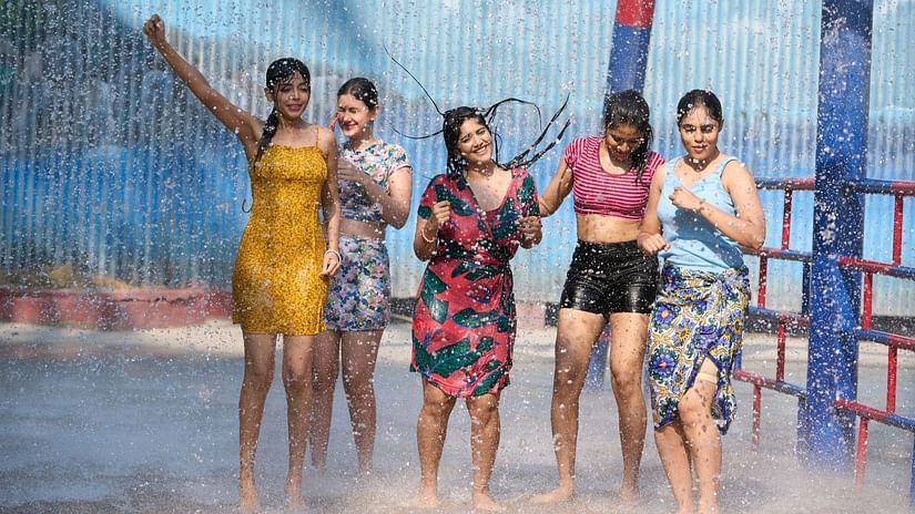 Group of women enjoying a splash zone under mist and water sprays at a water park.