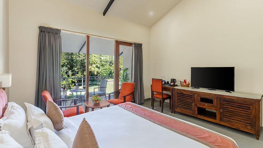 corner view of the luxury cottage room at the aranya vilas featuring a king size bed along with a television screen opposite to it