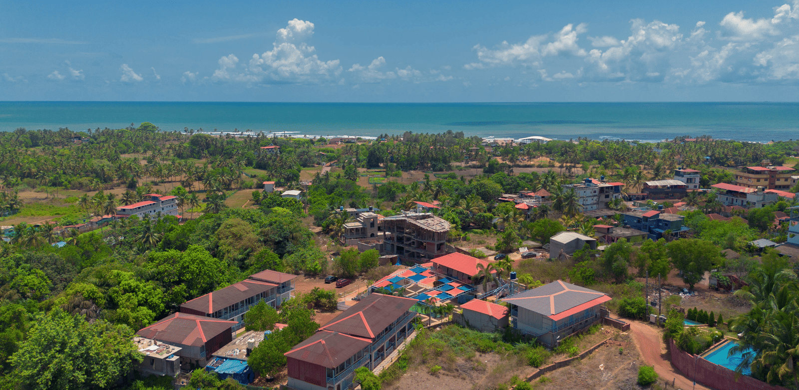 An aerial view of our resort, surrounded by lush green trees with Morjim Beach visible at the edge - Perfectstayz Koko Maya