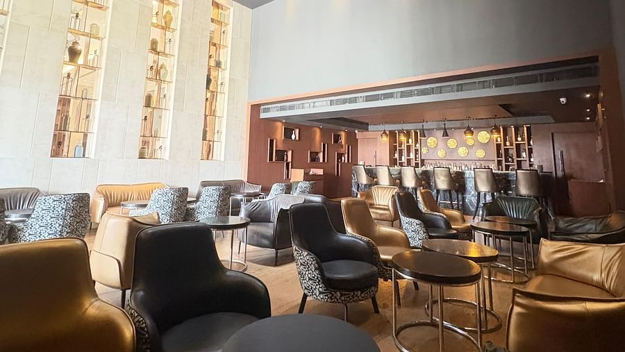 A high-angle shot of a bar with a large, geometric chandelier, focusing on the lighting and seating arrangement.