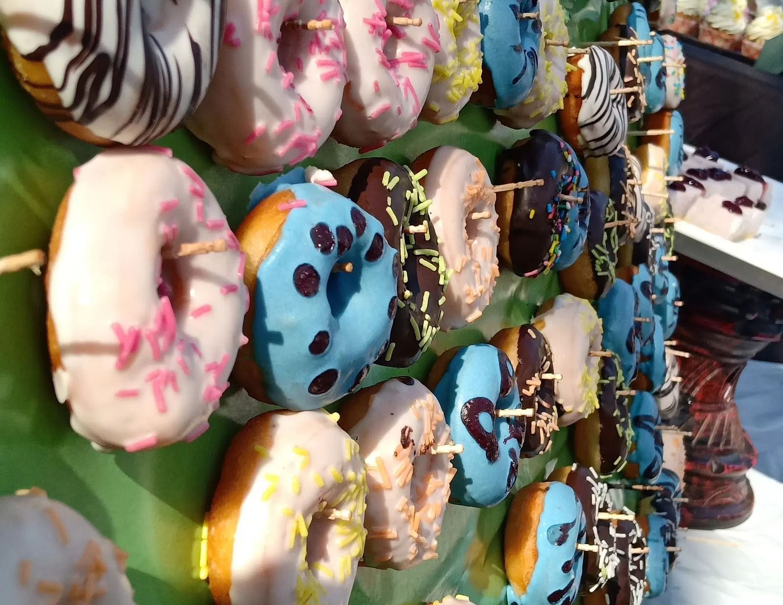 Close-up shot of colourful doughnuts hanging on a wall in an outdoor setting.