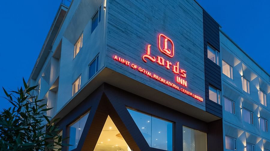 The Lords Inn Udaipur hotel is shown at dusk, with its modern architecture and illuminated signage visible against the dark blue sky.