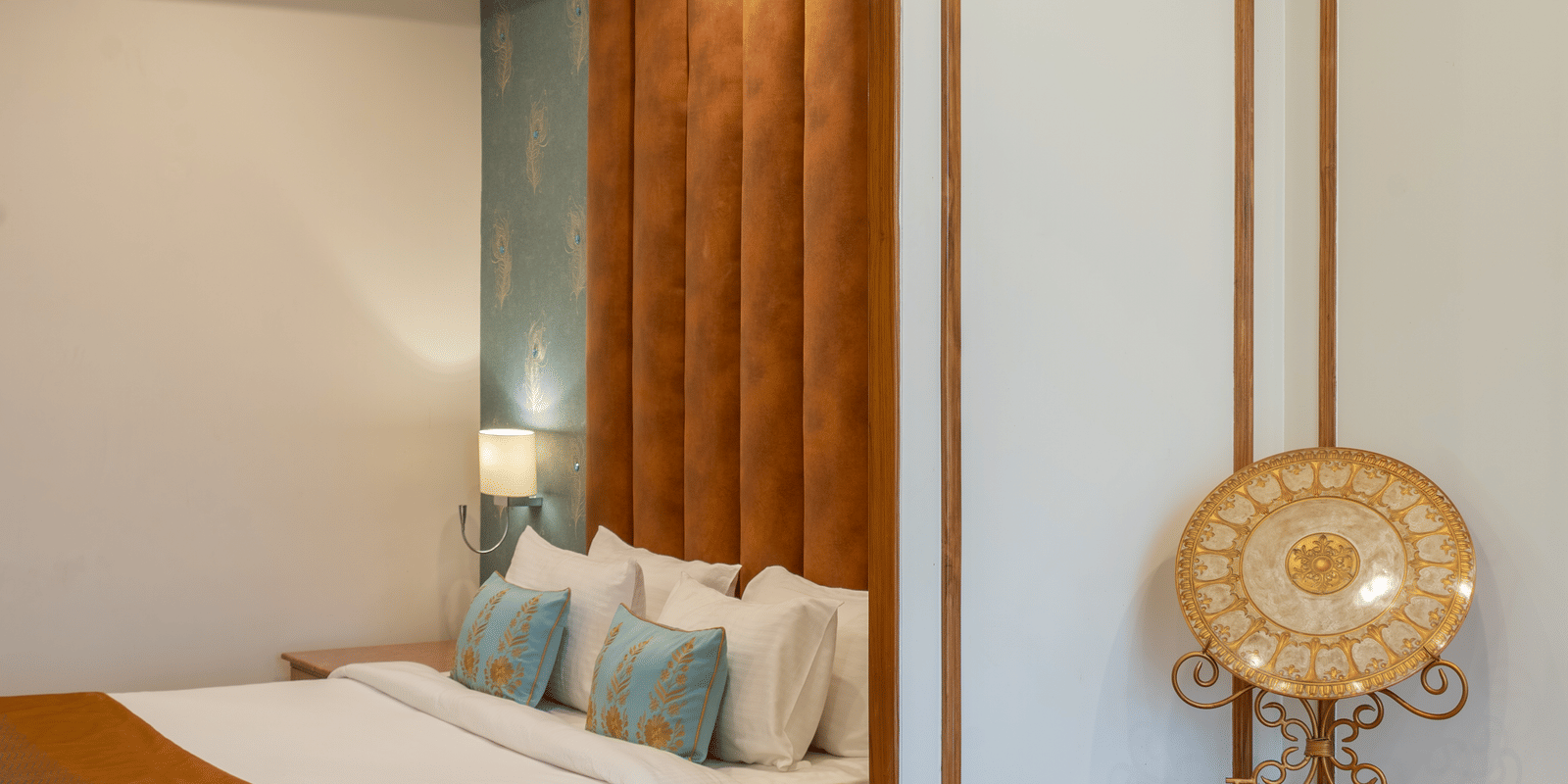 Corner of a stylish bedroom with a bed, vanity table, and mirror, featuring gold trim and a velvet headboard at Hotel Hukam's Lalit Mahal.