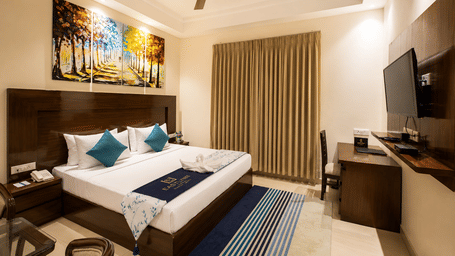 Executive Double room with a large bed, artwork and a work desk at Eastlynn Resort, Rishikesh.