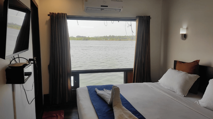 Bedroom with a queen bed, curtains, and window overlooking the water at Paradise Lagoon Resort, Udupi.