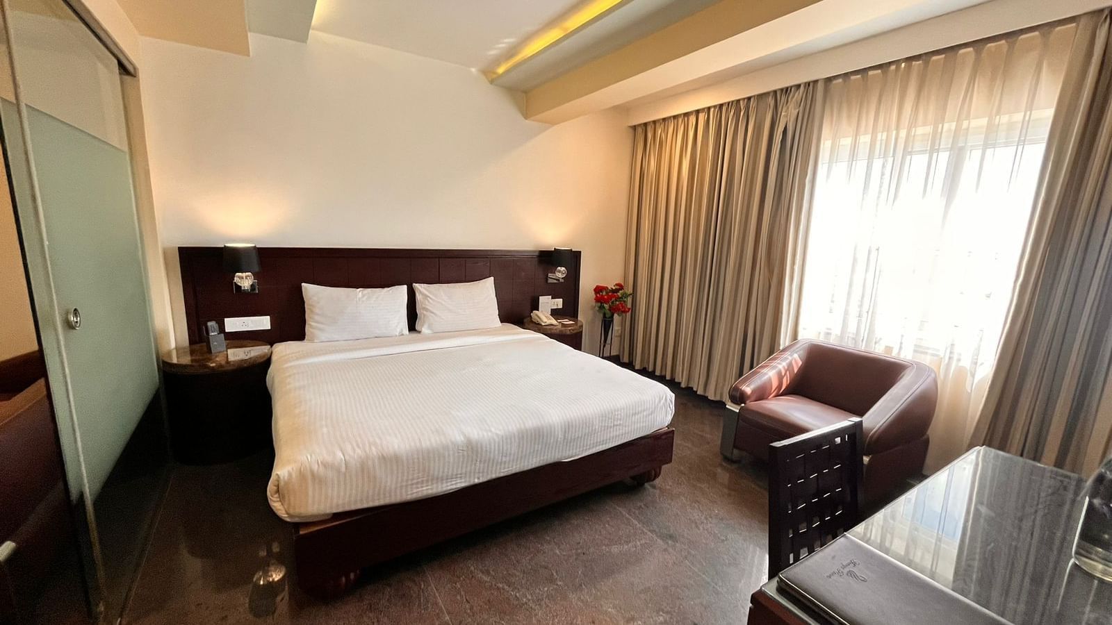 Executive suite room featuring a plush bed with nightstands attached to headboard and a couch placed next to the window