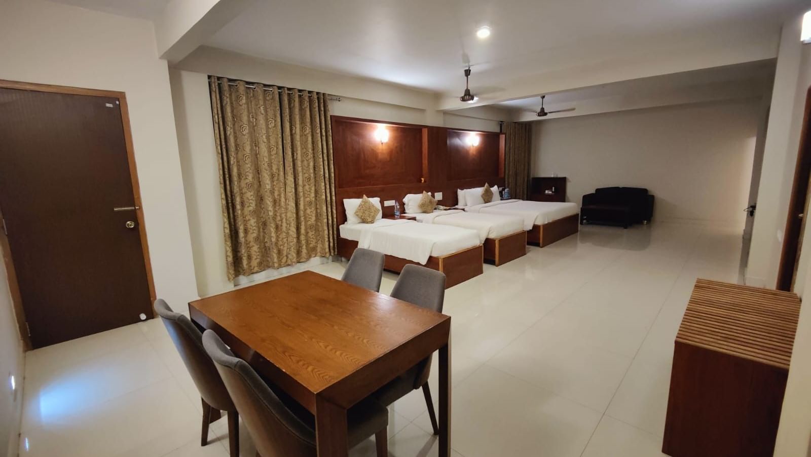 Woodstock Resorts, Coorg Deluxe Family Room bathroom with glass shower, sleek fixtures, toilet, and wooden shelving for essentials.