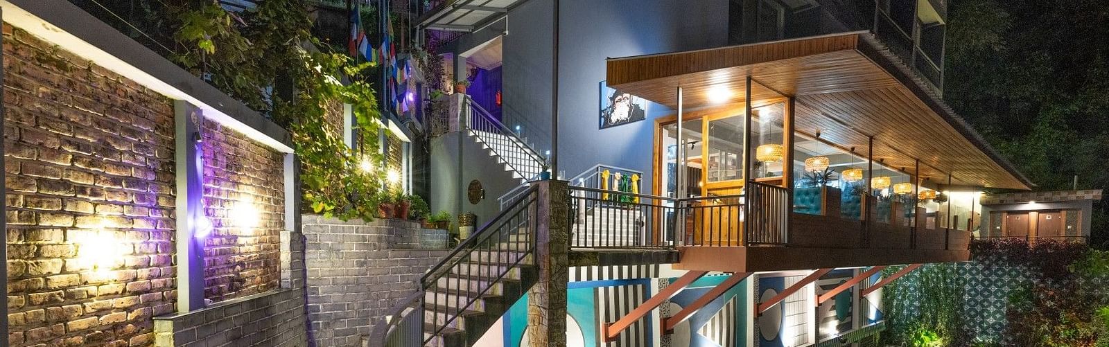 An image of a entrance which has a swimming pool on one side and the entrance leads to a well lit building - Avianna Group of Hotels & Resorts
