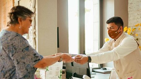 A man offering a visiting card to an elderly woman at Karma Chalets.