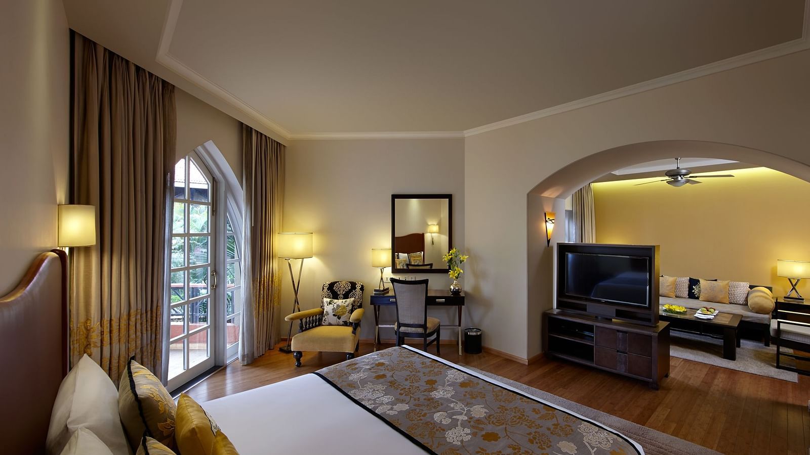 a double bed with a tv and living room opposite it inside Suite - Caravela Beach Resort Goa