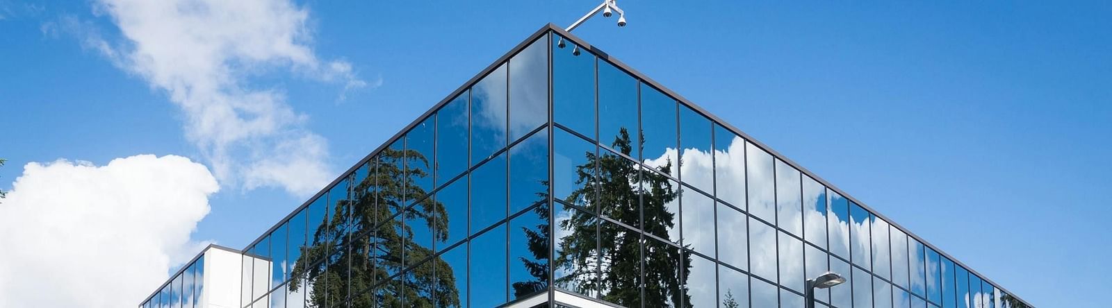 Image of  a building with glass walls and a clear sky in the background.