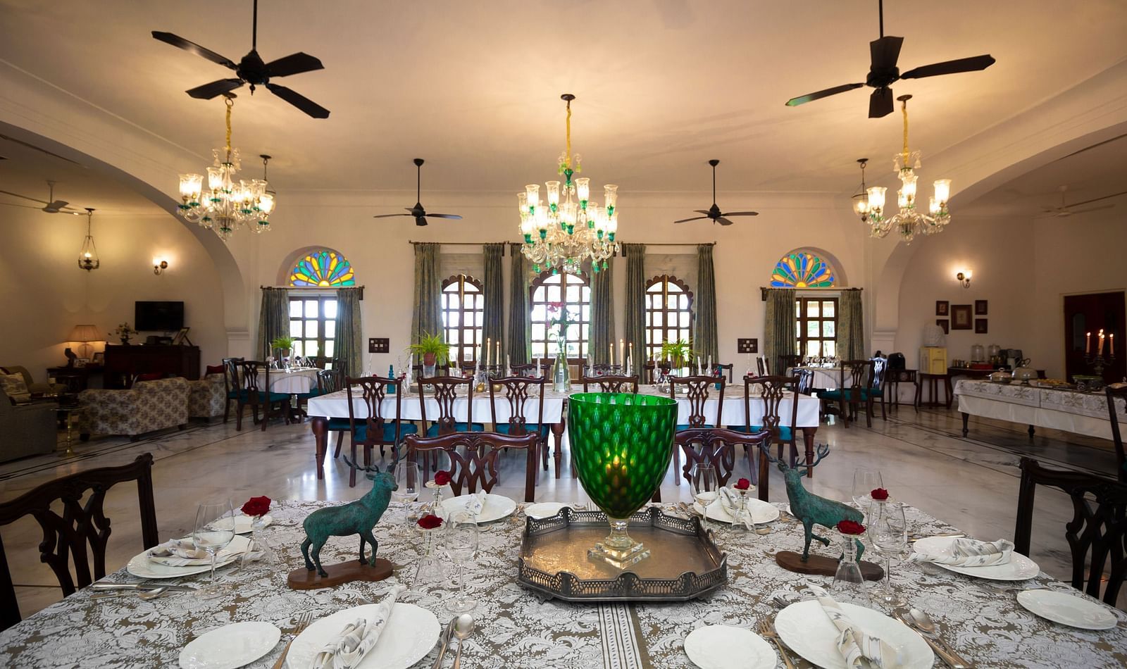 image showcaing the Indoor dining arrangement at Dev Shree, Deogarh with elegant chandeliers hanging from the top