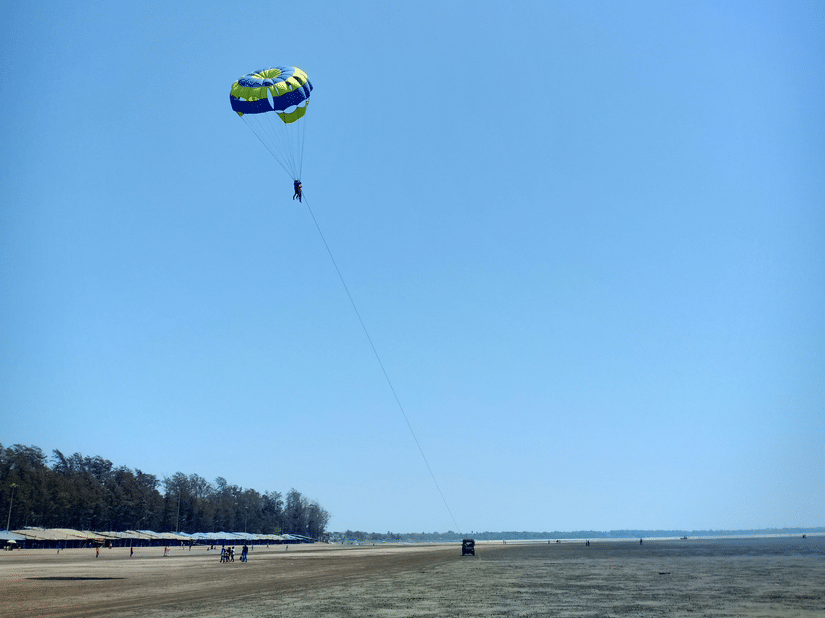 Parasailing adventure in Daman with a colourful parachute soaring above the wide sandy shoreline and open coastline