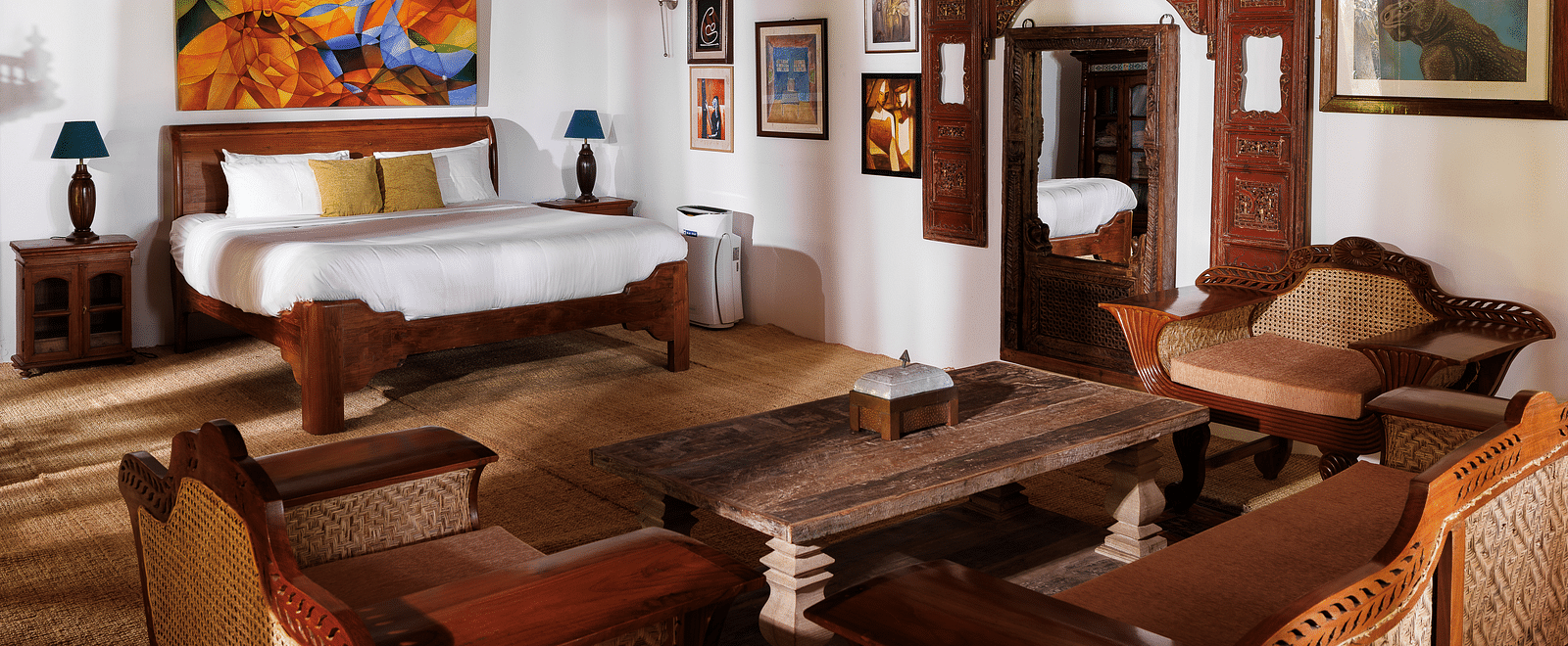A wooden interior room with wooden furnitures such as a bed, a sofa set, a coffee table, and paintings - BluSalzz Villas - Muhamma Resort, Alleppey