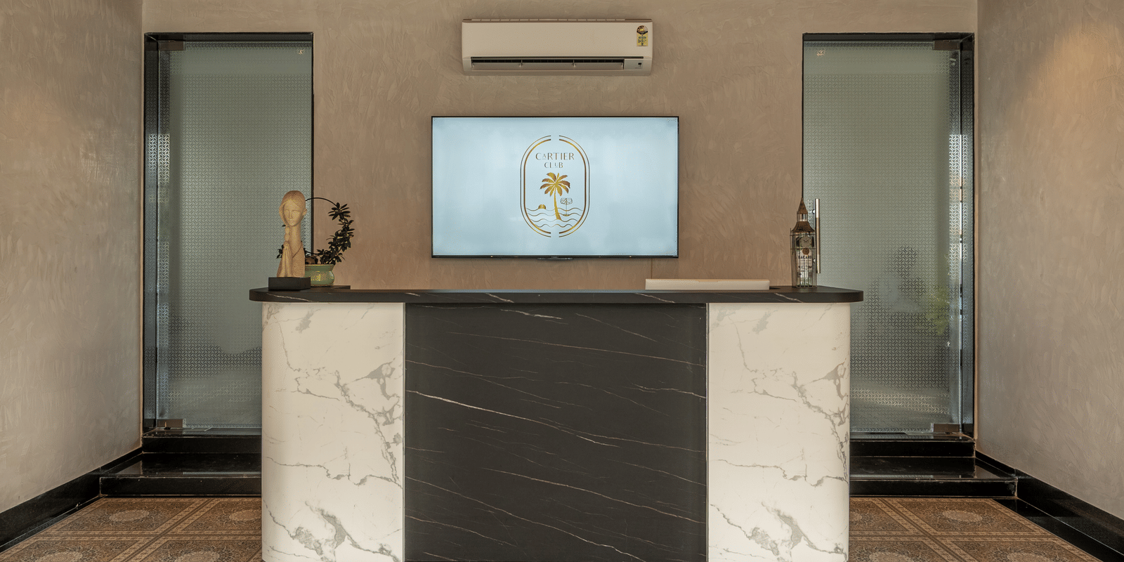 Small indoor counter or bar area with a TV screen above a dark counter, featuring a patterned floor and red ceiling at Hotel Hukam's Lalit Mahal.