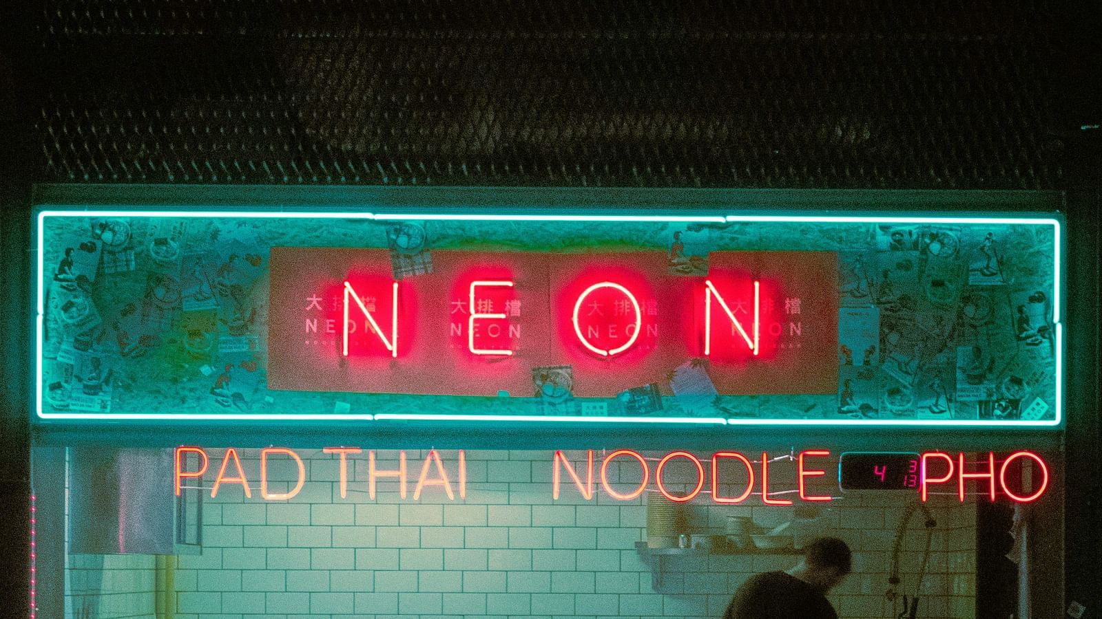 A picture of a restaurant with neon signs of Pad Thai, Noodle and Pho.