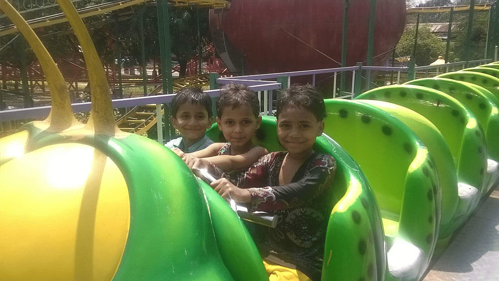 3 children on an amusement park ride during daytime