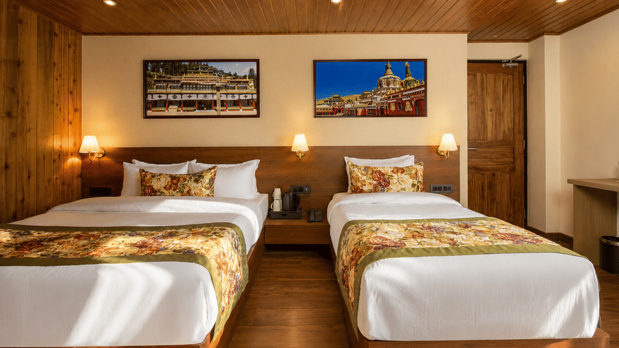 A king size bed, a single bed, a wardrobe, a window with curtains, and a television at Valmere Lungta Boutique Hotel & Spa, Darjeeling.