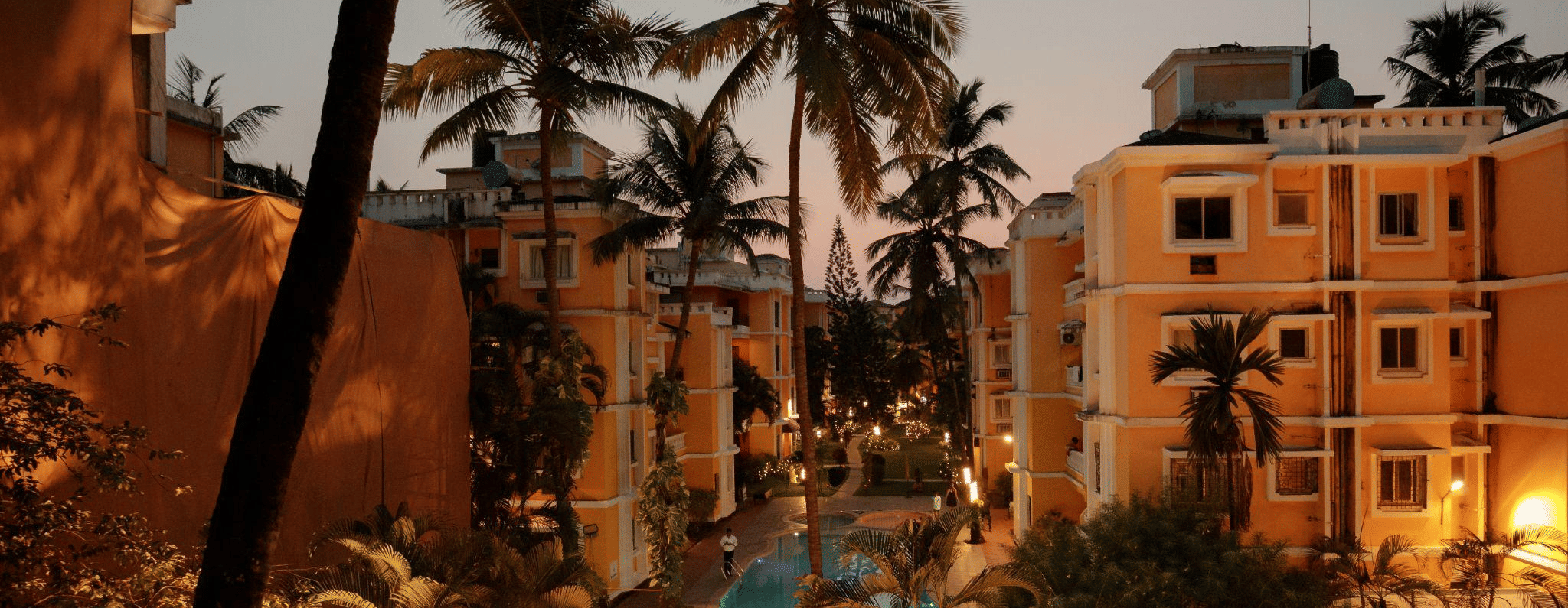 A view of the hotel building with the pool during dusk.