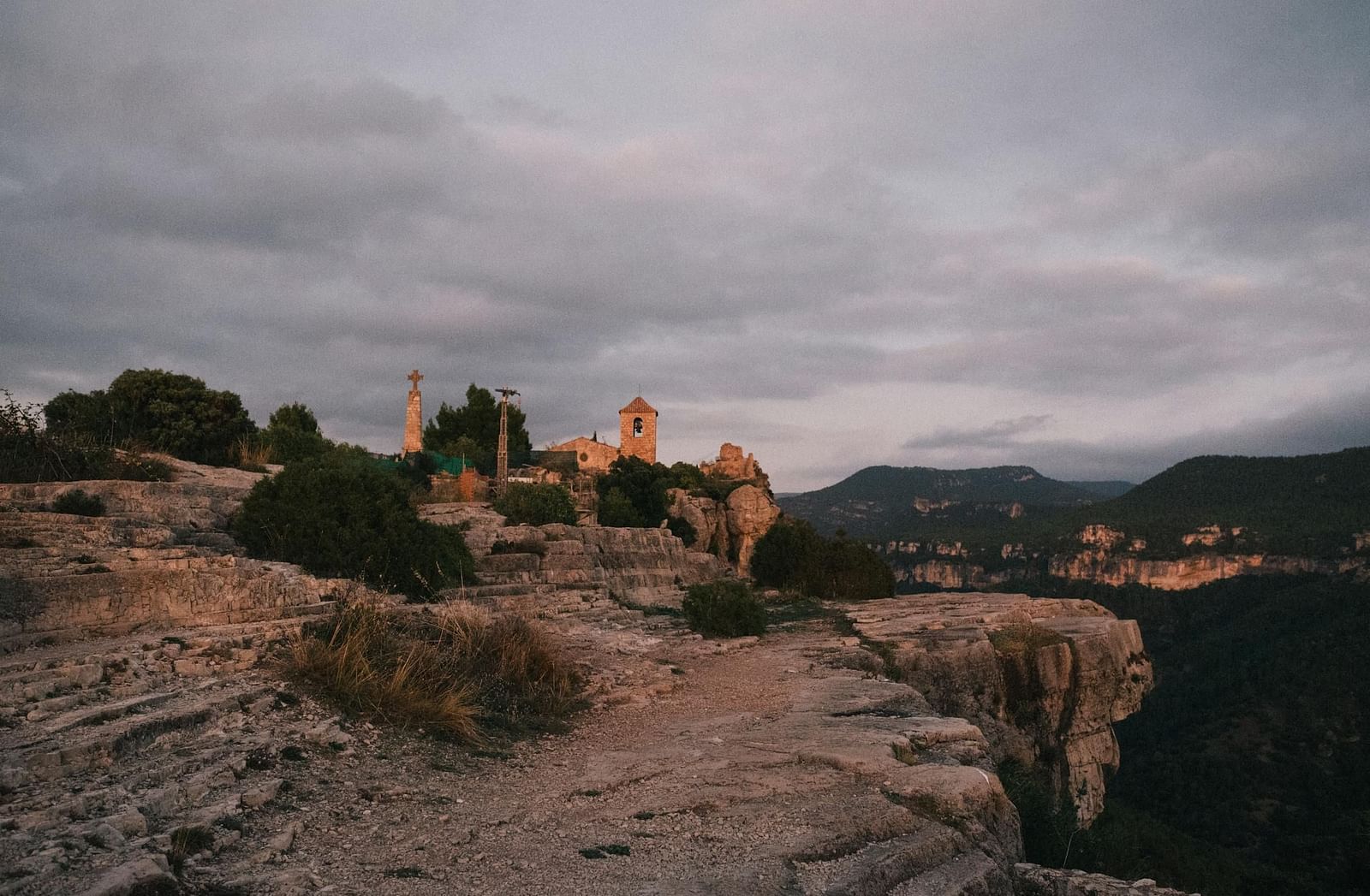 A rugged mountaintop with a distant structure perched on its edge.