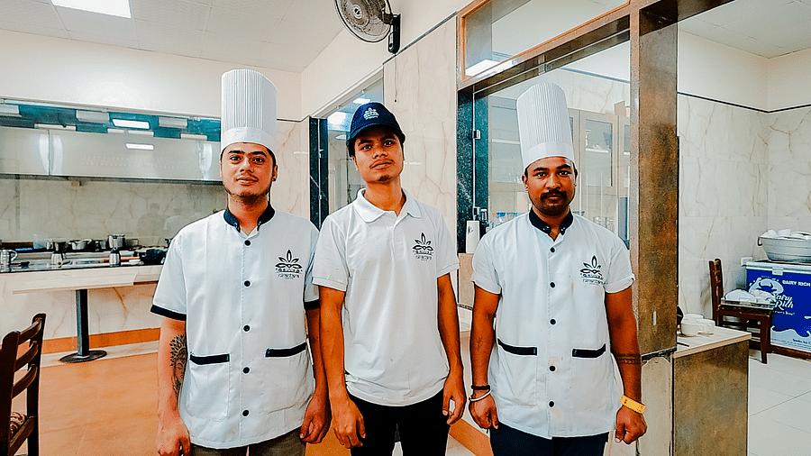 Three chefs in white uniforms in a kitchen at Nirantara Resort & Spa, possibly preparing a meal.