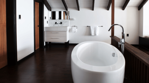 A clean, minimalist bathroom features a white toilet and a sink, with a large mirror and natural light.