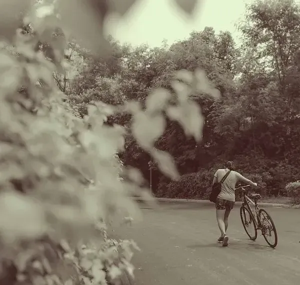 Sepia-toned photo of a person cycling on a garden path at Karma Chalets.