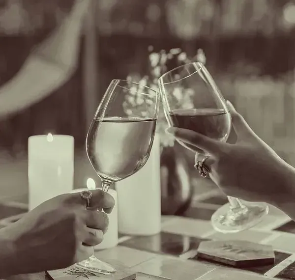 Sepia-toned image of hands holding wine glasses during a meal at Karma Chalets.