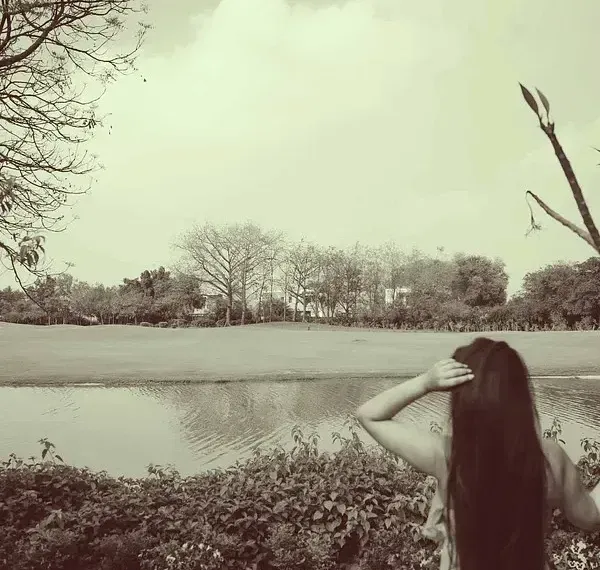Sepia-toned photo of a person standing by a water body at Karma Chalets.