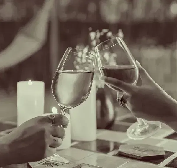 Sepia-toned image of hands holding wine glasses during a meal at Karma Chalets.