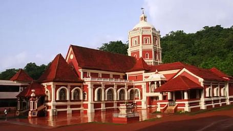 A  building with red and white facade, windows and a clock tower.