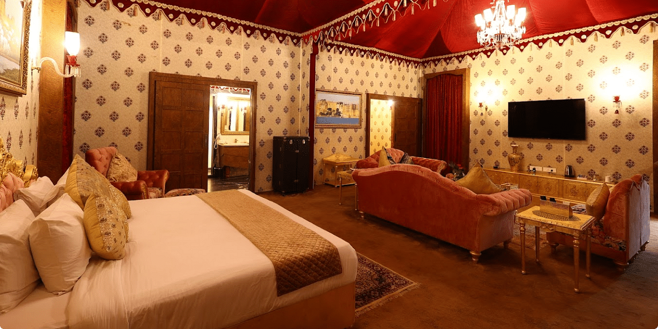 Image of a room with a bed and chandeliers hanging from the ceiling at Rajasthali Resort & Spa Jaipur.