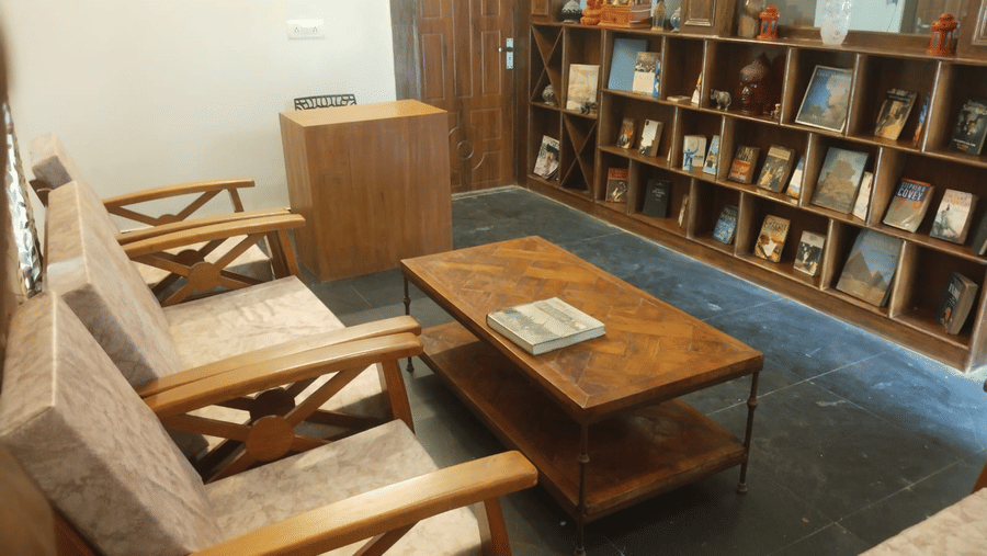 Library lounge with wooden armchairs, coffee tables, bookshelves and reading materials.