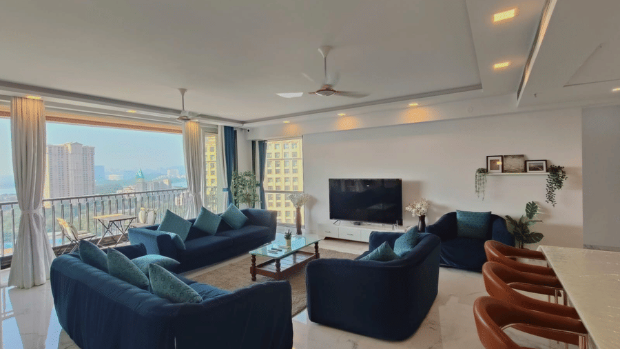 1hall and living room area of Maxxvalue Hotel, Chitranjan Tower, Powai with blue themed couch and a dining table in the corner of the room