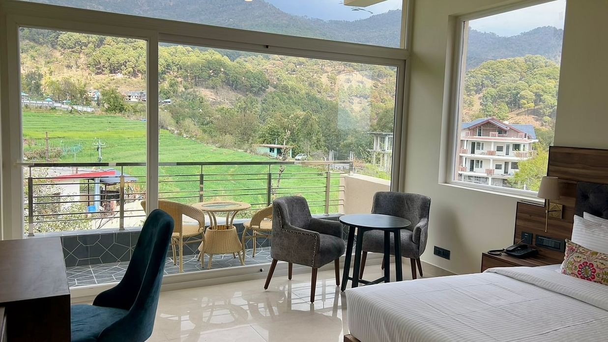 Room with seating area and bed and large windows overlooking the lush mountains