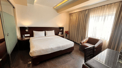 Executive suite room featuring a plush bed with nightstands attached to headboard and a couch placed next to the window