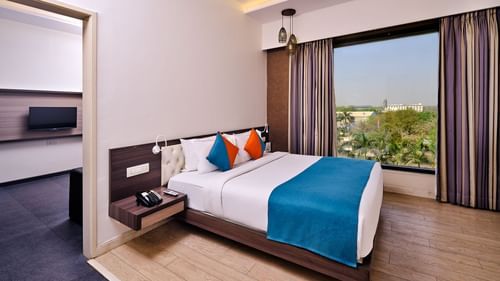 Pride Biznotel Manjusar - a luxury bedroom with balcony view and posh interior