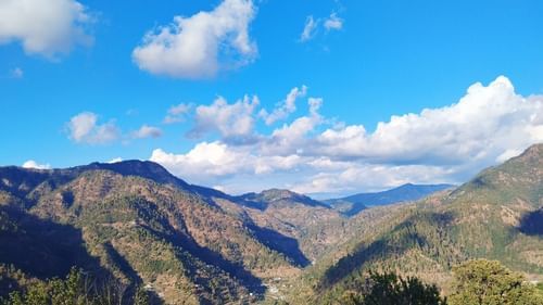 View of lush mountains with a blue sky with could scattered around - Ramgarh Bungalows, Nainital.