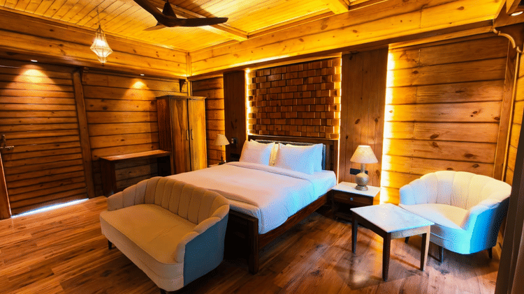A bedroom at The Baagh Ananta Elite, Ranthambore featuring a king size bed, upholstered bench, single sofa, and small coffee table.  