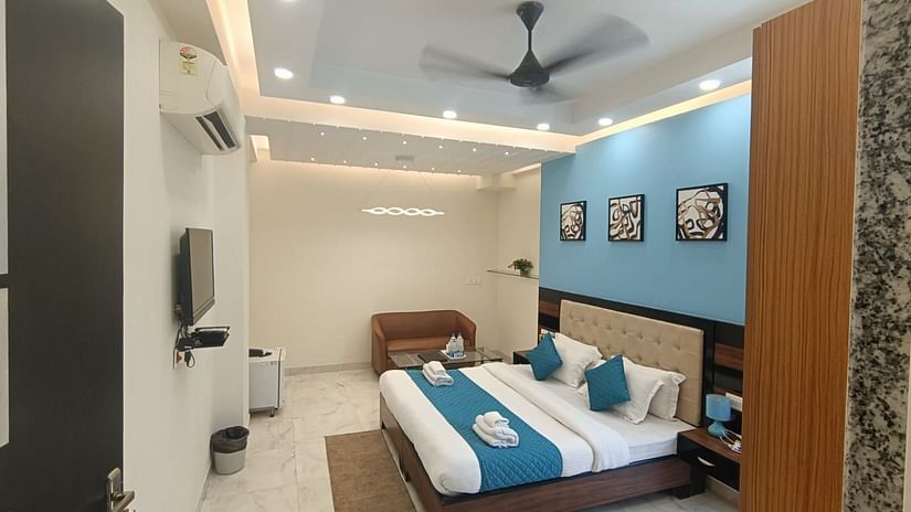 An interior view of a hotel room with a bed, seating area, and television - Asian Suites Cyber Park, Gurgaon.